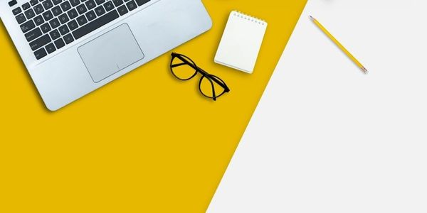 a laptop, glasses, diary, and coffee cup on the table 