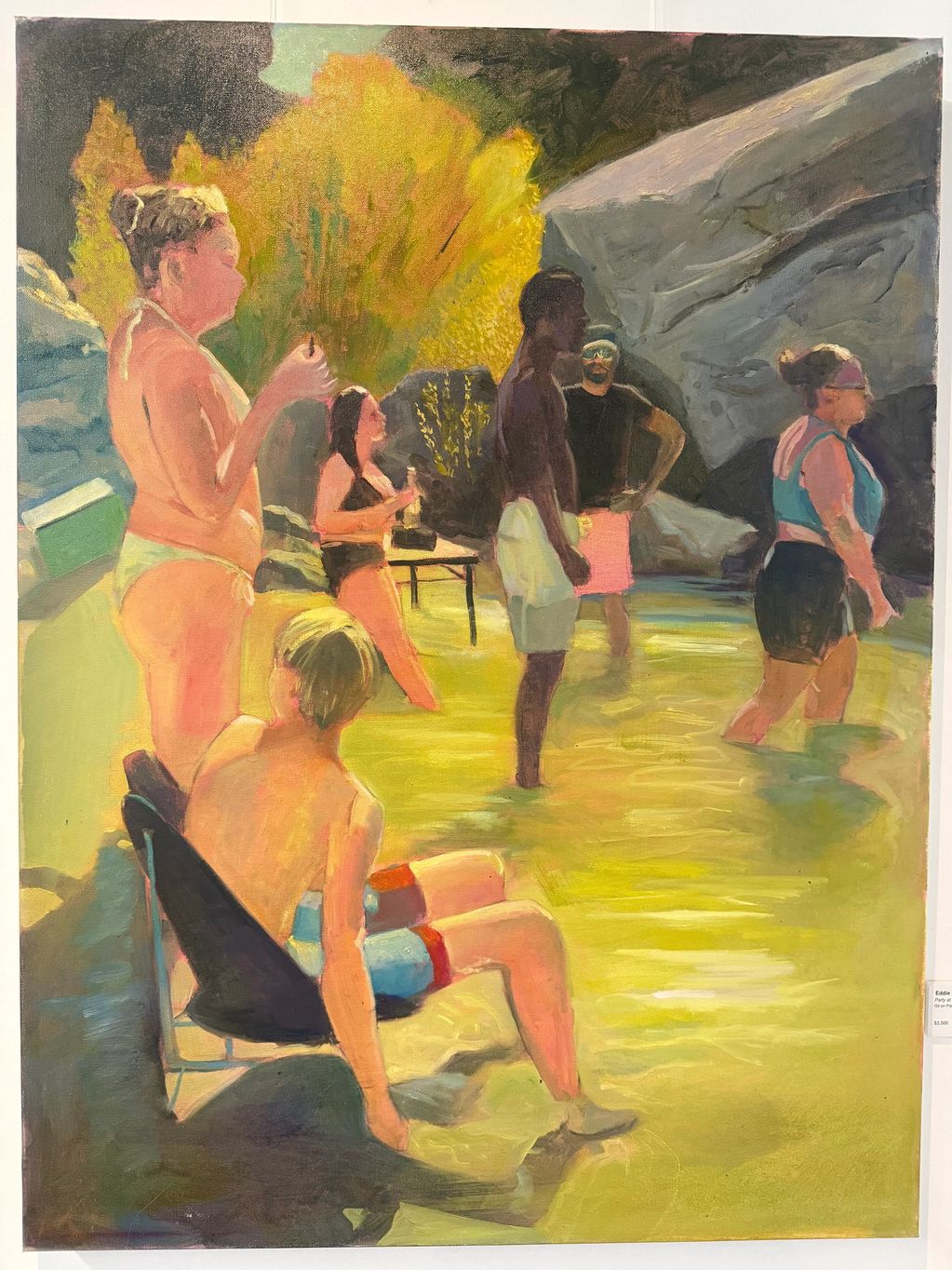 People enjoying a sunny day in shallow water surrounded by rocks and trees.