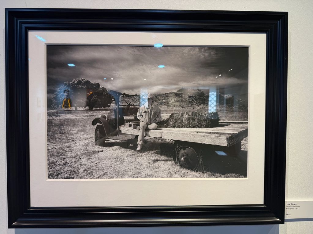 Black and white photo of a person sitting on an old flatbed truck in a rural field.