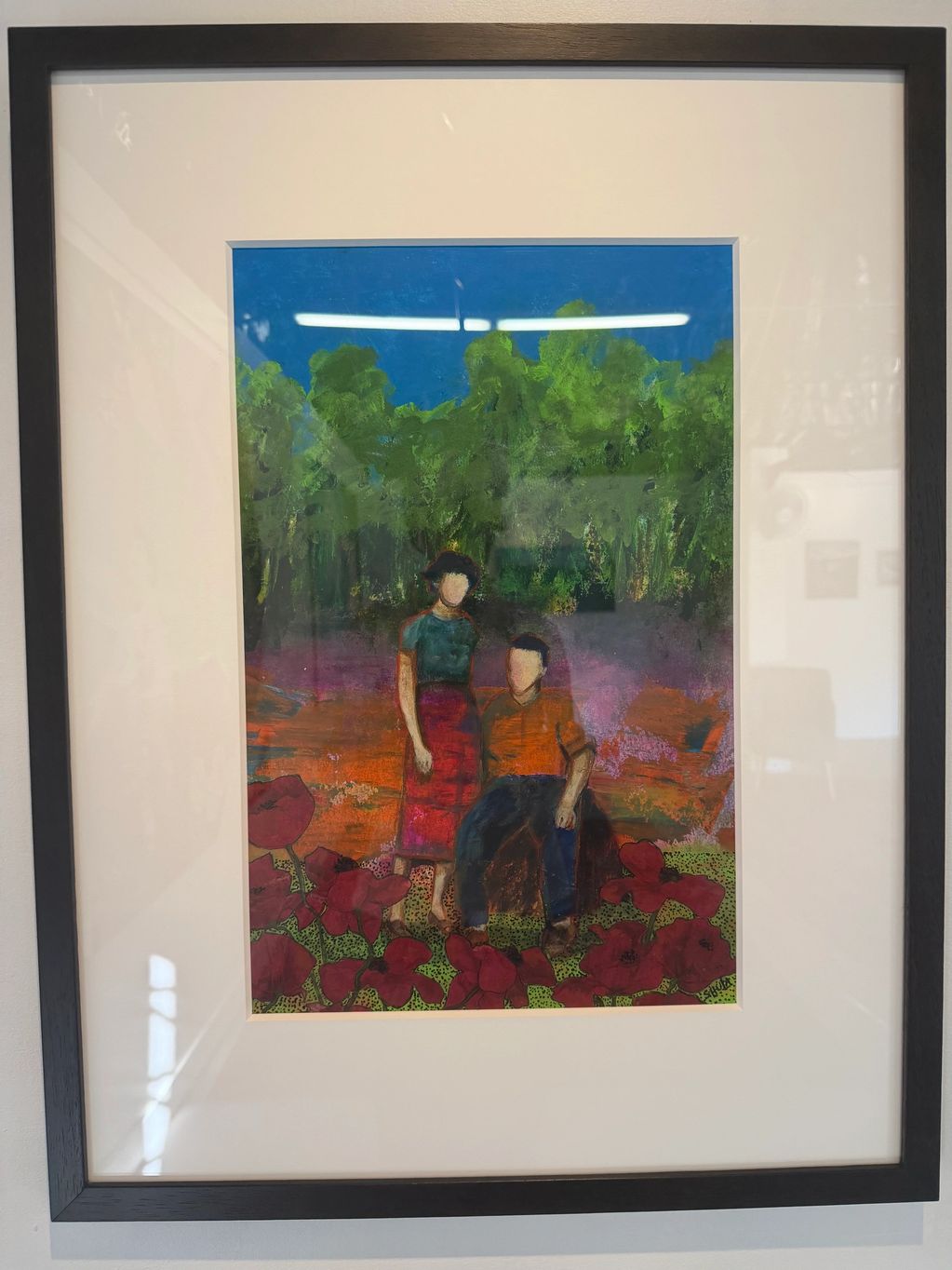 Framed painting of faceless couple in colorful landscape with red flowers.