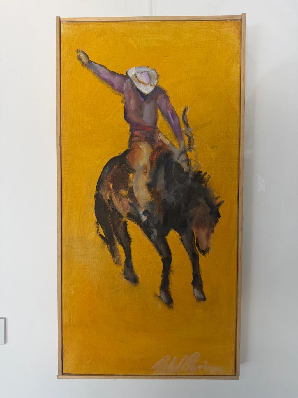 Painting of a cowboy riding a bucking horse on a yellow background.