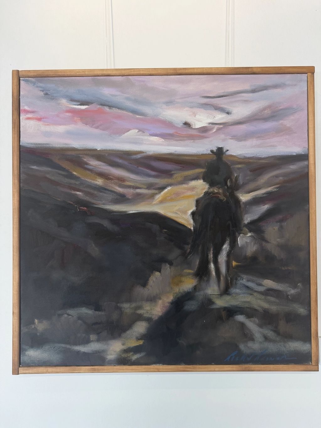 A lone cowboy rides through a moody, colorful landscape at dusk.
