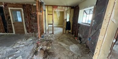 Room under heavy renovation with exposed walls and debris.