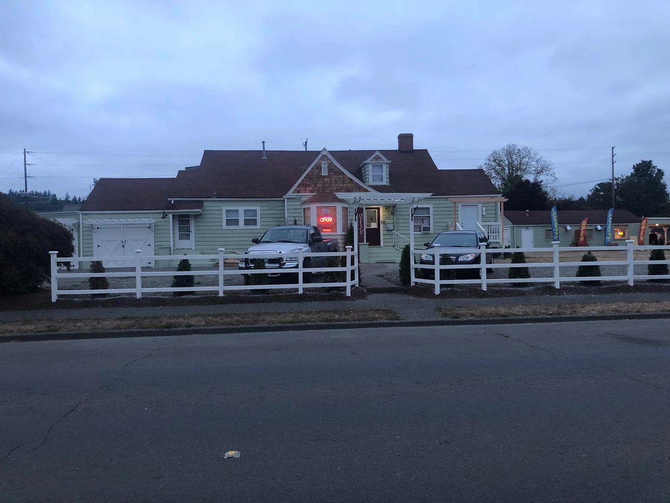 Small motel with cars parked outside and neon open signs at dusk.