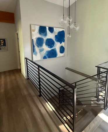 Modern stair railing with abstract blue and white wall art.