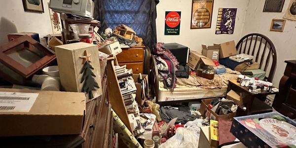 Cluttered room filled with boxes and furniture.