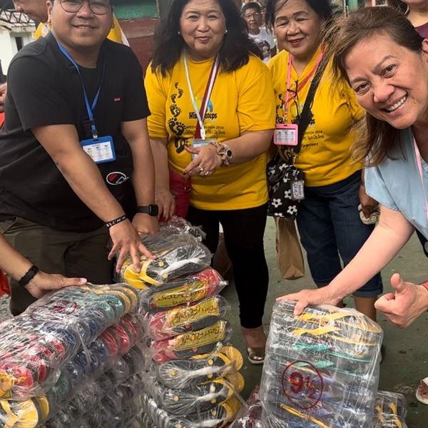 Group of people smiling and distributing packaged goods.