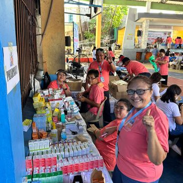 Volunteers at a community health event distributing medicines and supplies.