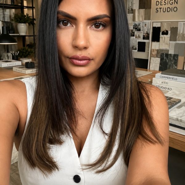 Confident woman with straight hair in a white sleeveless top at a design studio.