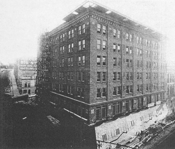 Black and white photo of an old multi-story brick building.