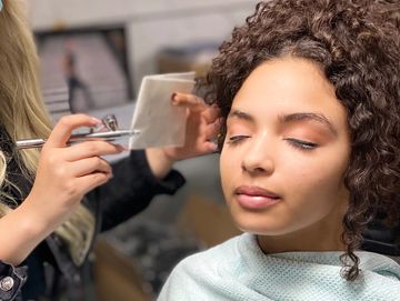 A woman make-up artist spraying on the clients face