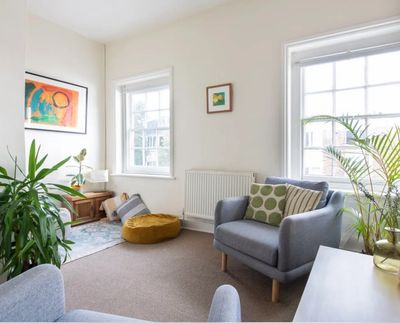 Bright living room with cozy seating, plants, and colorful artwork.