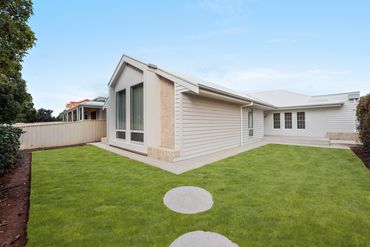 Modern house with large windows and a green lawn.