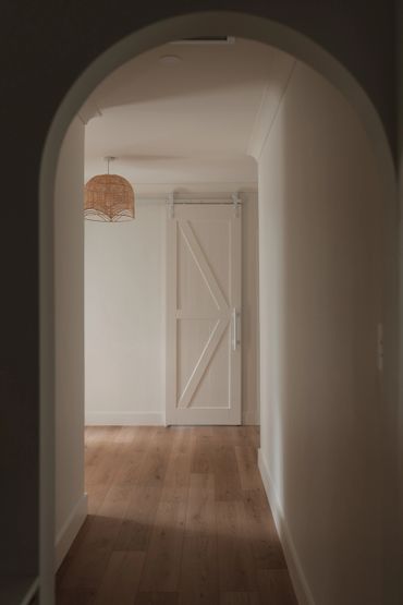 Minimalist hallway with wooden floor and white sliding barn door.