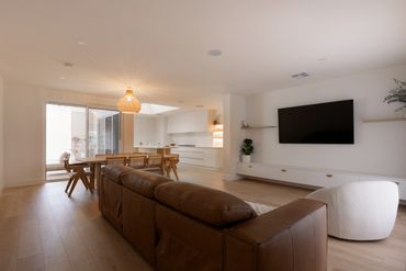 Modern living room with brown leather sofa and mounted TV.