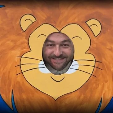 Man's face in a cartoon lion cutout.