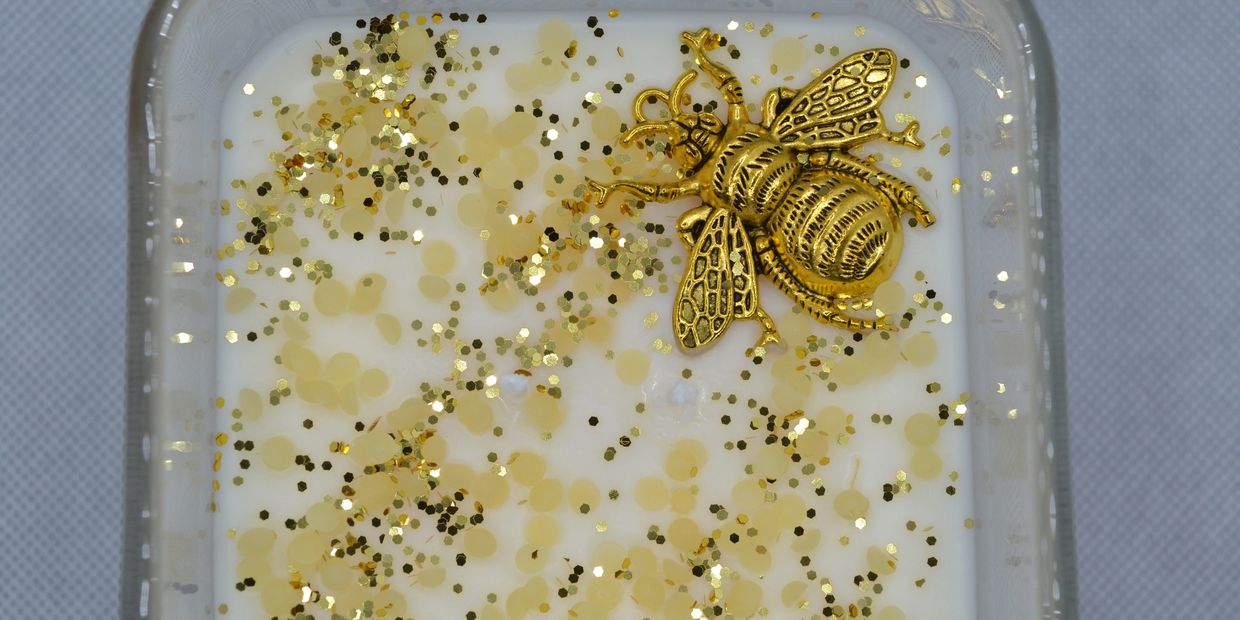Bee charm and beeswax with gold glitter in a square candle.