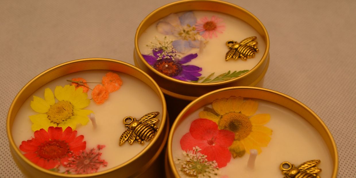 Bee charm and pressed flowers in a candle, each candle is unique in flowers used and arrangement.