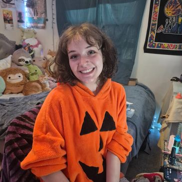 Young woman smiling in an orange pumpkin hoodie.