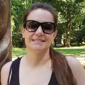 Woman wearing sunglasses outdoors smiling.