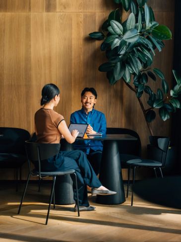 Two people having a discussion in a modern wooden-paneled room.
