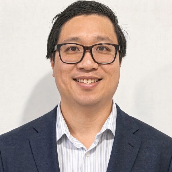 Smiling man wearing glasses and business attire.