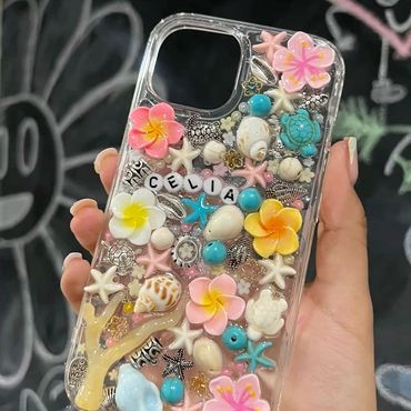 Colorful seashell and flower decorated phone case with beach-themed charms.