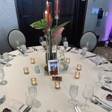 Elegant round table set with candles, glassware, and heart-shaped decor for a formal event.