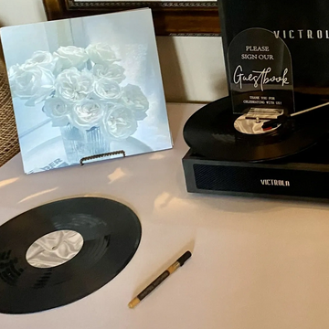 A Victrola record player with a guestbook sign and vinyl record on a table.