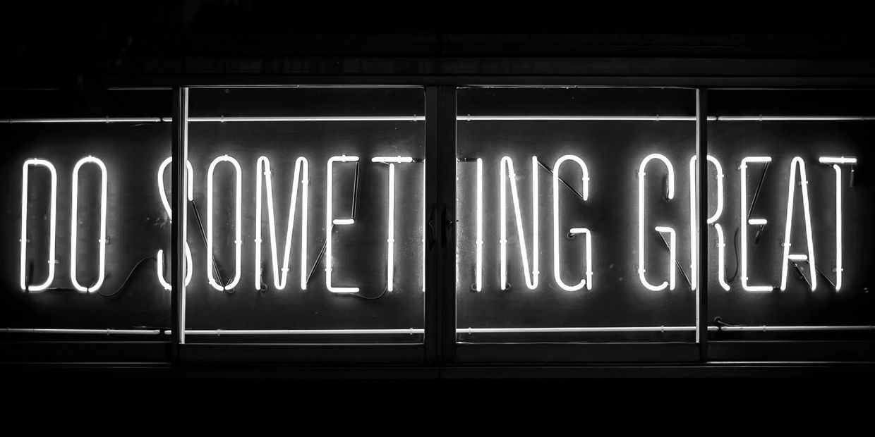 Neon sign glowing with the phrase 'DO SOMETHING GREAT'.