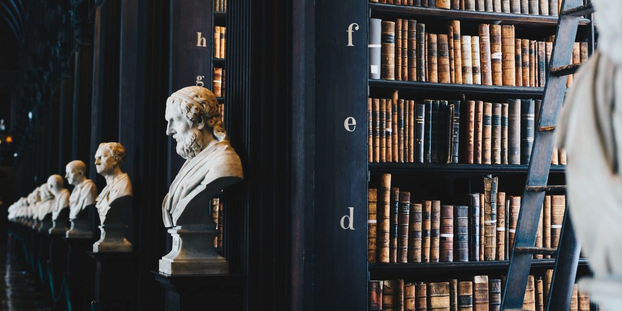 Library stacks adorned with busts of famous individual from history.