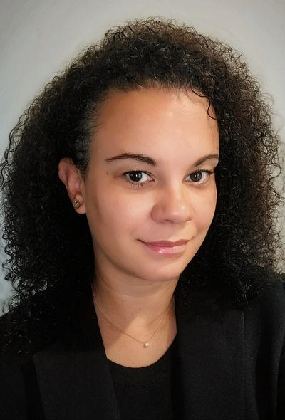 Portrait of a woman with curly hair wearing a black jacket.