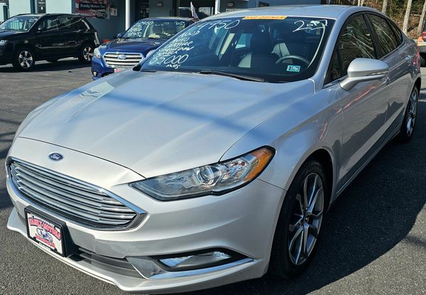 Silver Ford sedan parked at a dealership with pricing details on the windshield.