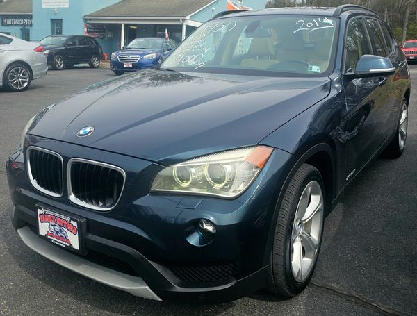 2014 BMW X1 parked at a car dealership with price written on the windshield.
