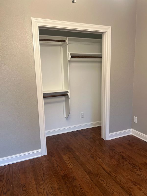 Empty walk-in closet with wooden floor and gray walls.