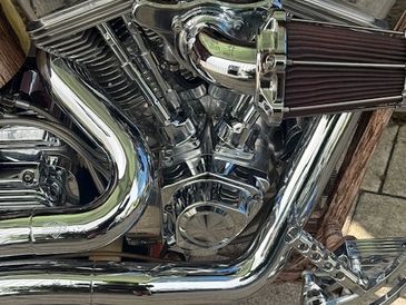 Close-up of a shiny chrome motorcycle engine with air filter and exhaust pipes.