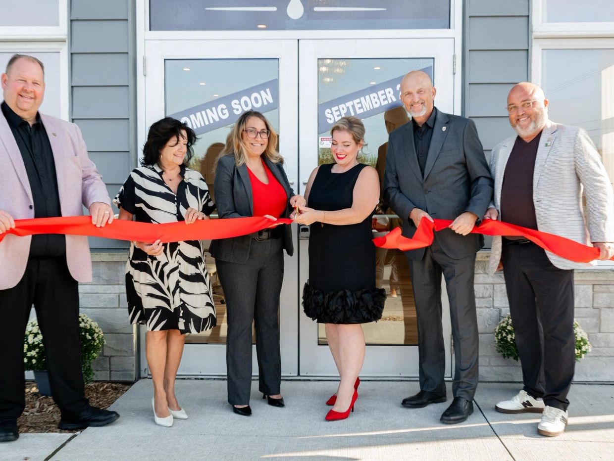 Group ribbon-cutting ceremony in front of a new store.