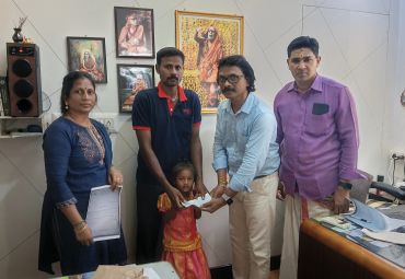 Group of people handing over a document to a young girl in an office setting.