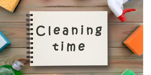 Notebook with 'Cleaning time' surrounded by sponges and cleaning spray.