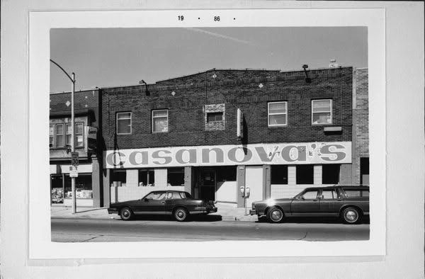 Black and white photo of Casanova's building with two parked cars outside.