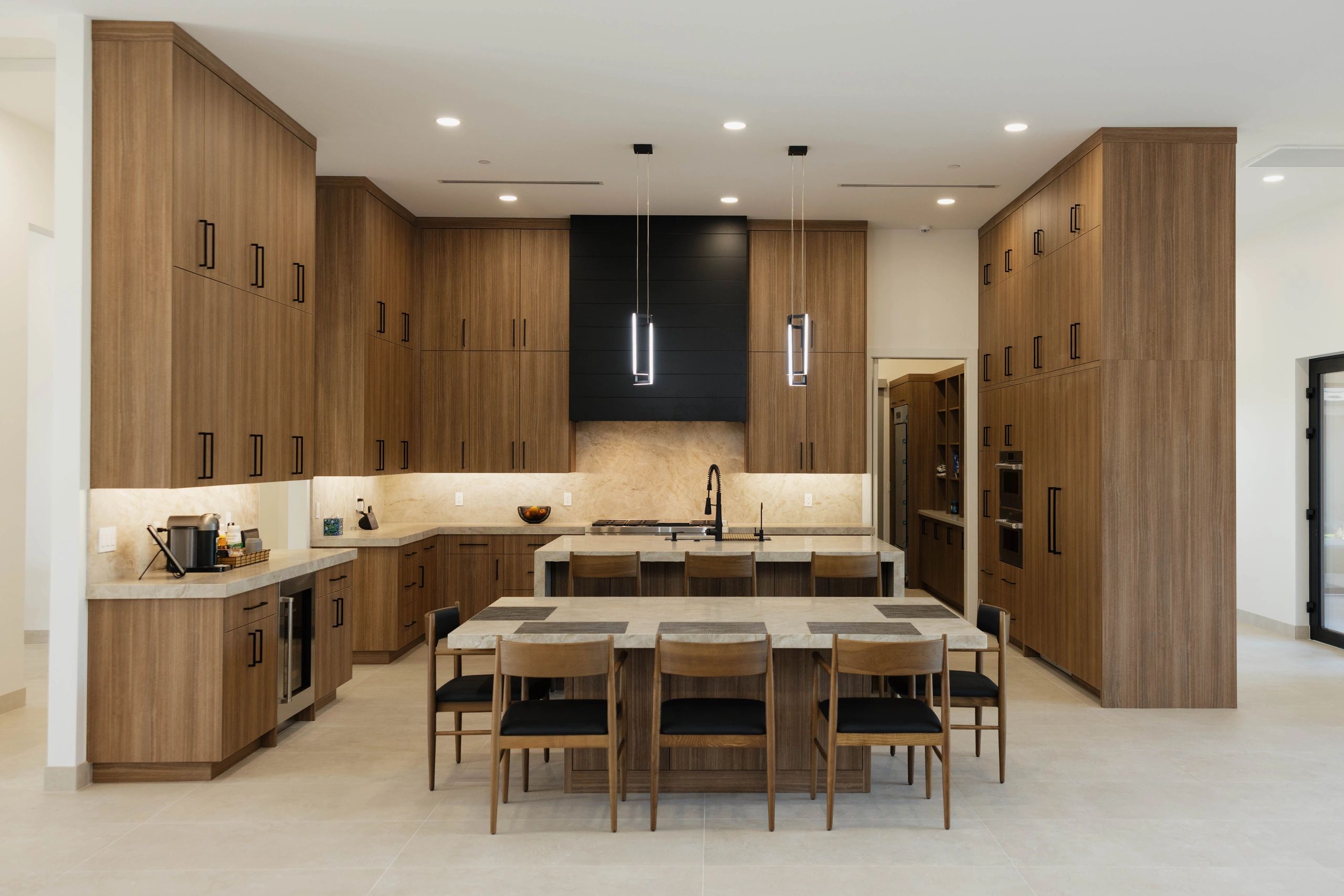 Modern kitchen with wooden cabinets, marble countertops, and pendant lights over an island.