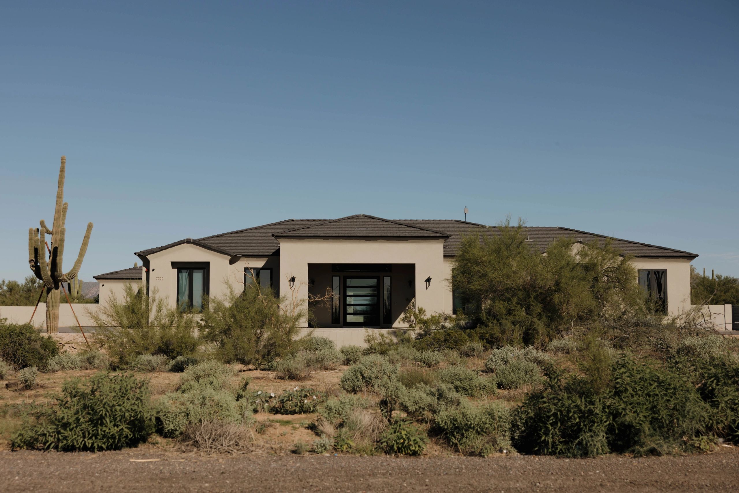 Modern desert home with cactus and clear blue sky.