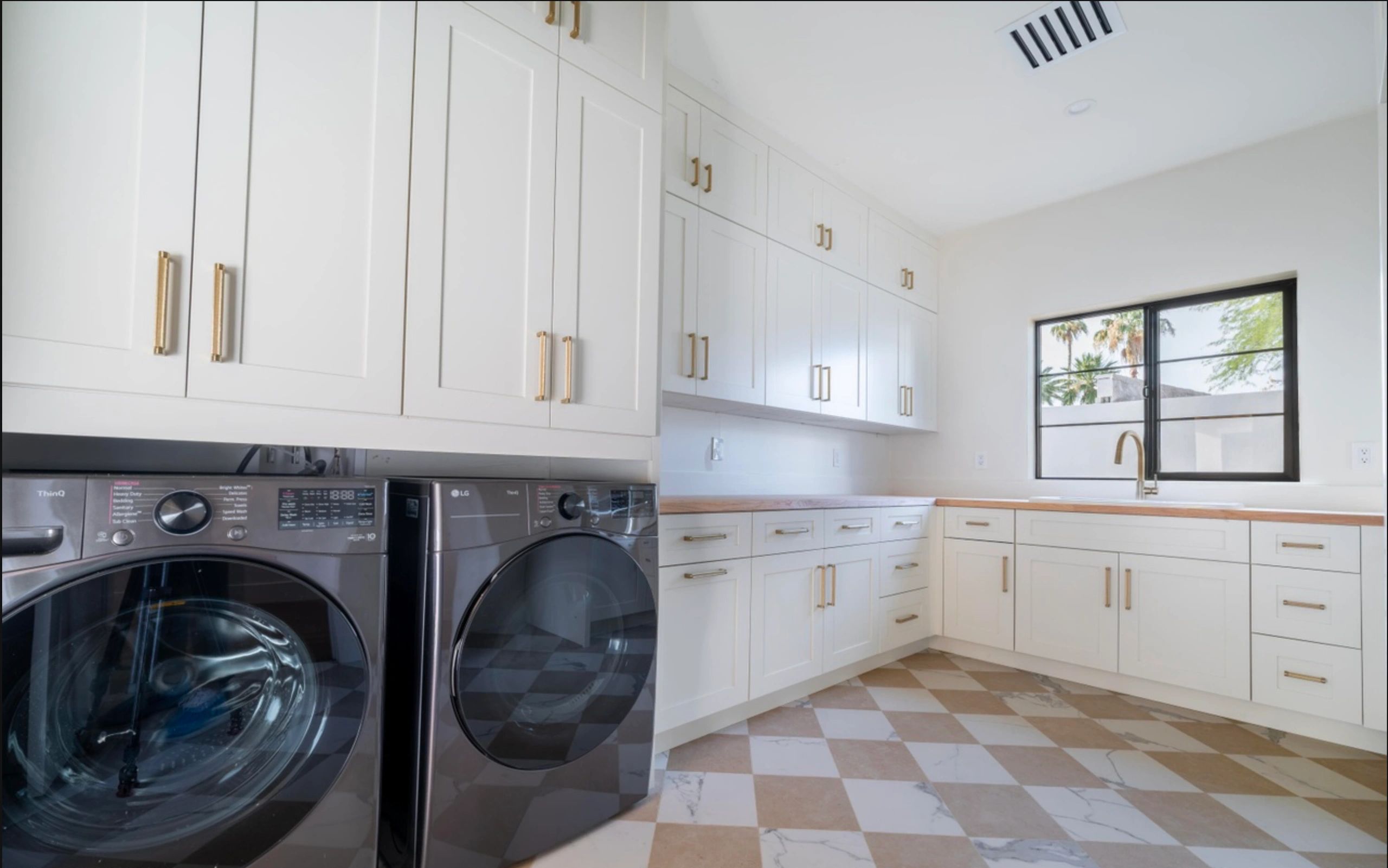Modern laundry room with white cabinets and checkered floor.