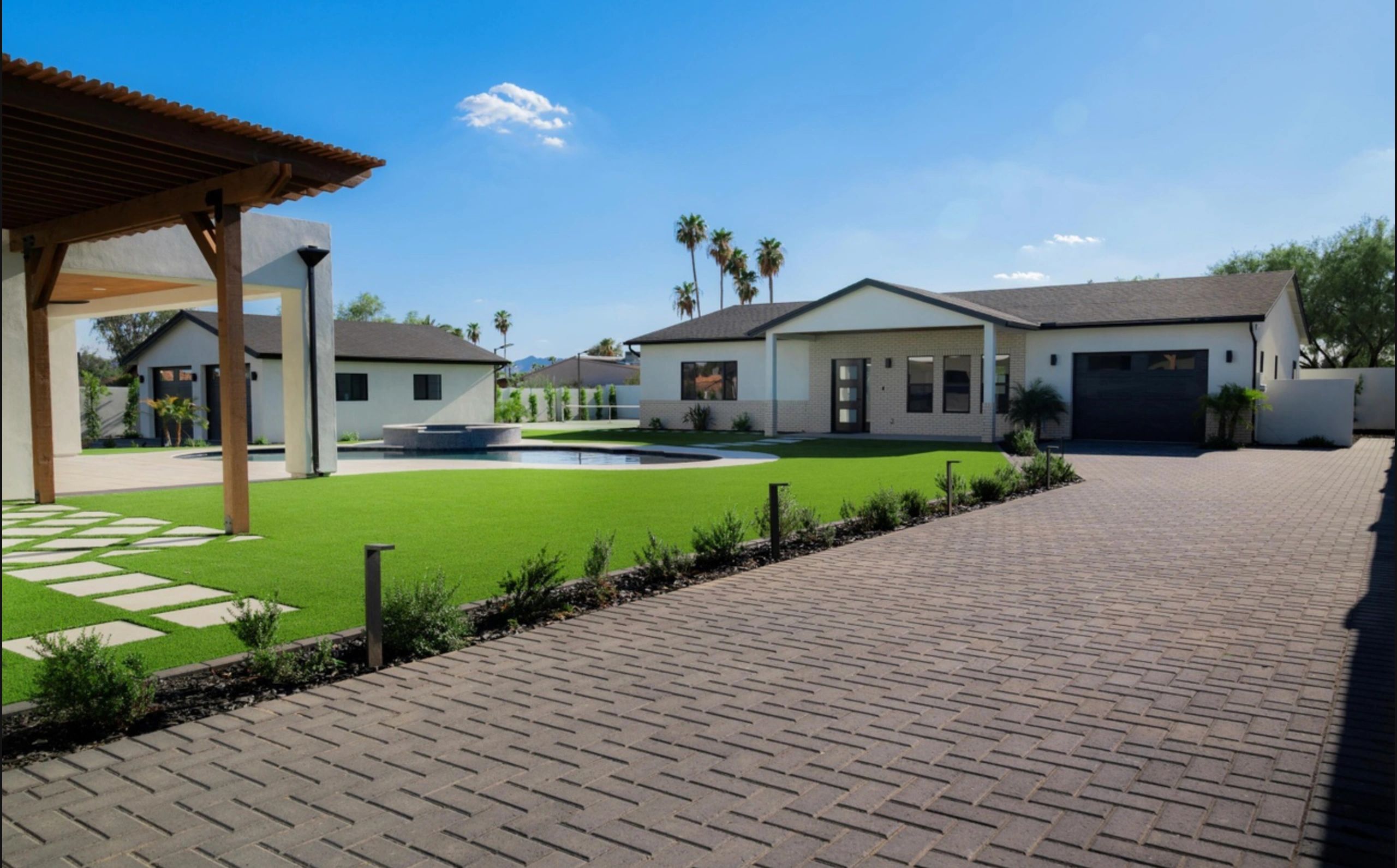 Modern house with pool and palm trees under clear blue sky.
