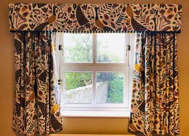 a pair of pencil pleated curtains with a matching pelmet with a pom pom trim