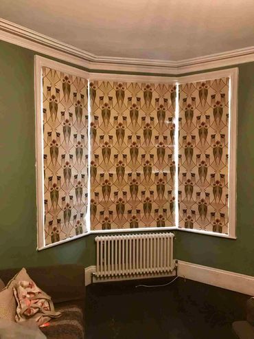 three roman blinds fit inside a bay window with the pattern matching across all thress