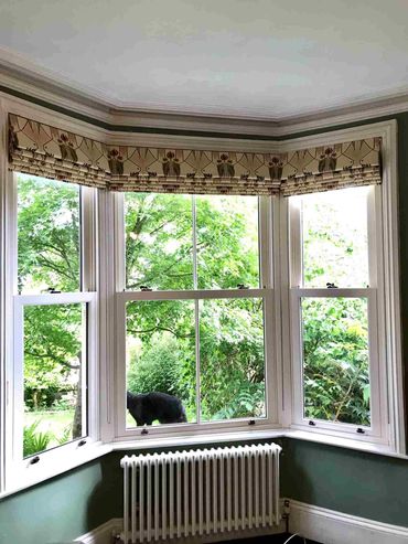 Three, interlined roman blinds, inside a bay window with the pattern matching across each of them
