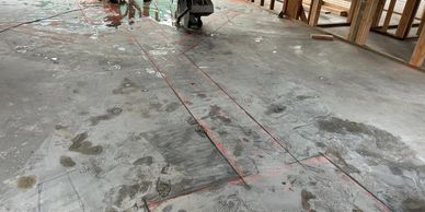 Construction site with concrete floor and tools, footprints, and wooden framing.
