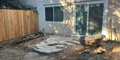 Backyard patio demolition with broken concrete and construction tools.
