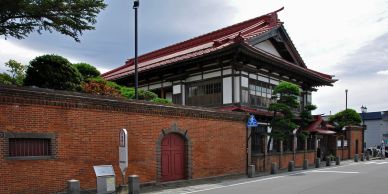 Traditional Japanese building with a red tiled roof behind a brick wall.